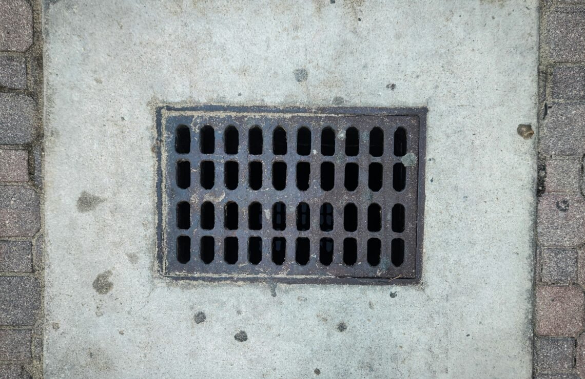 A grate on the side of a brick wall