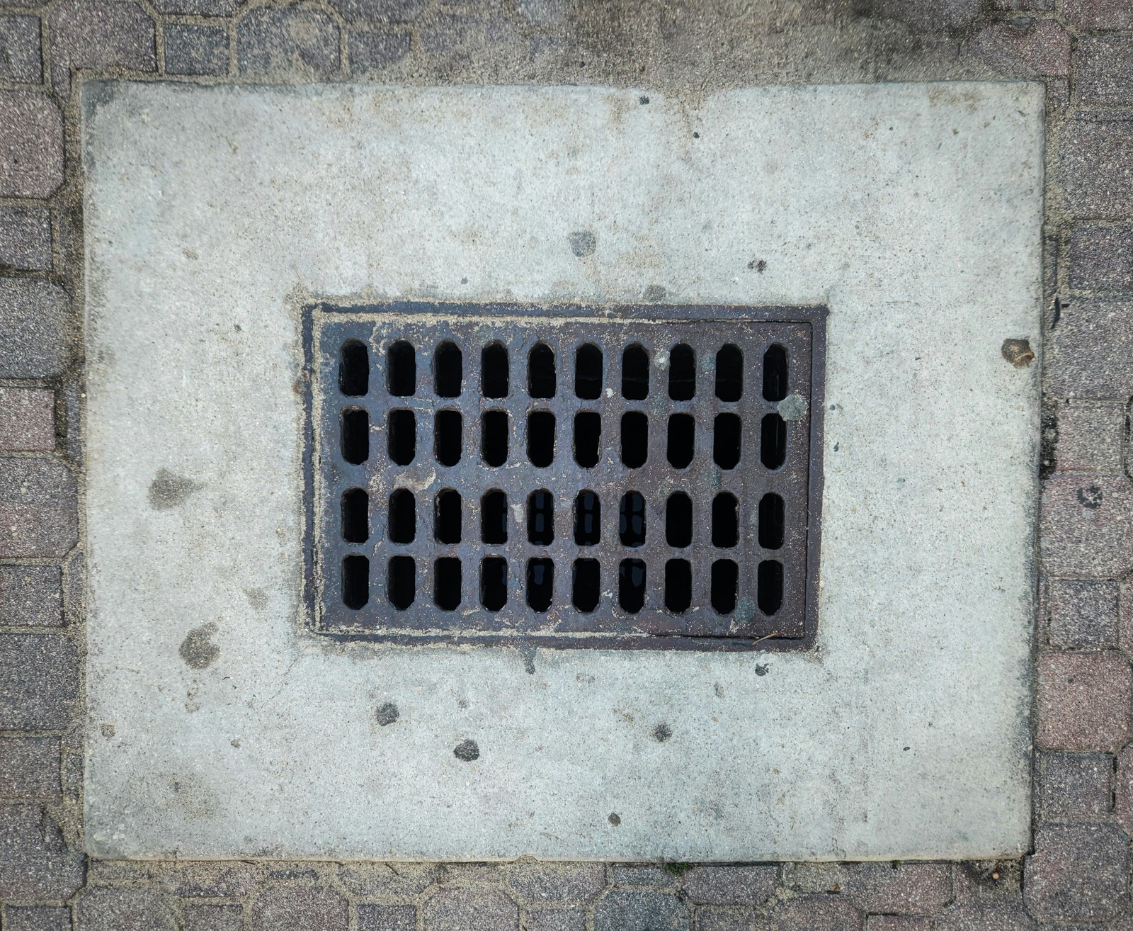 A grate on the side of a brick wall